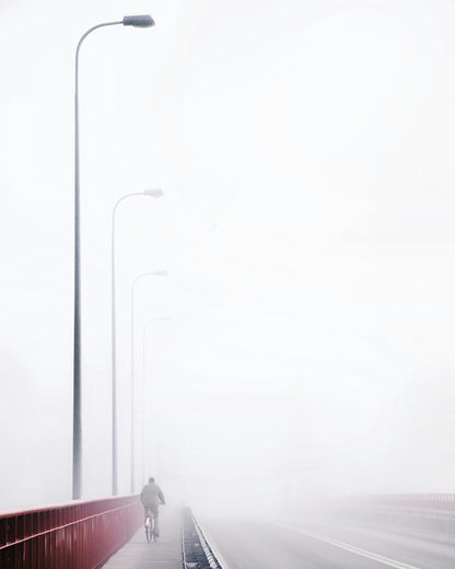 Cyclist on a Foggy Bridge