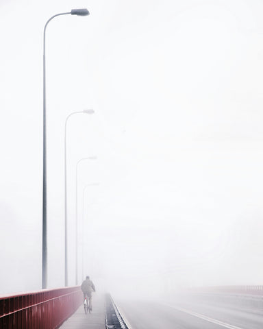 Cyclist on a Foggy Bridge