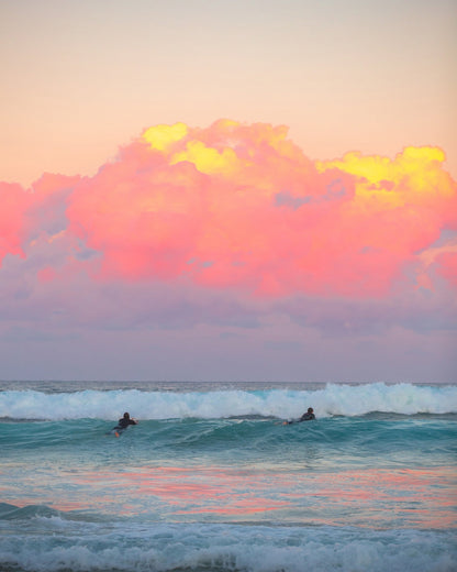 Surfers Ride The Waves At Sunset